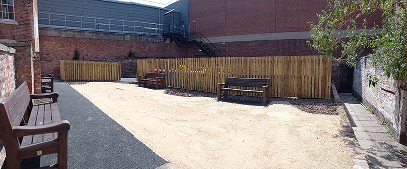 View of Feathers Lane with four brown benches and fencing